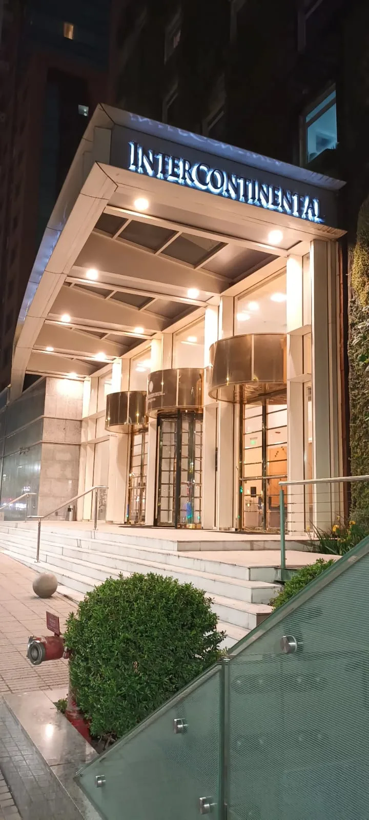 Eingangsbereich des Intercontinental Hotels bei Nacht mit beleuchteten Türen und Säulen