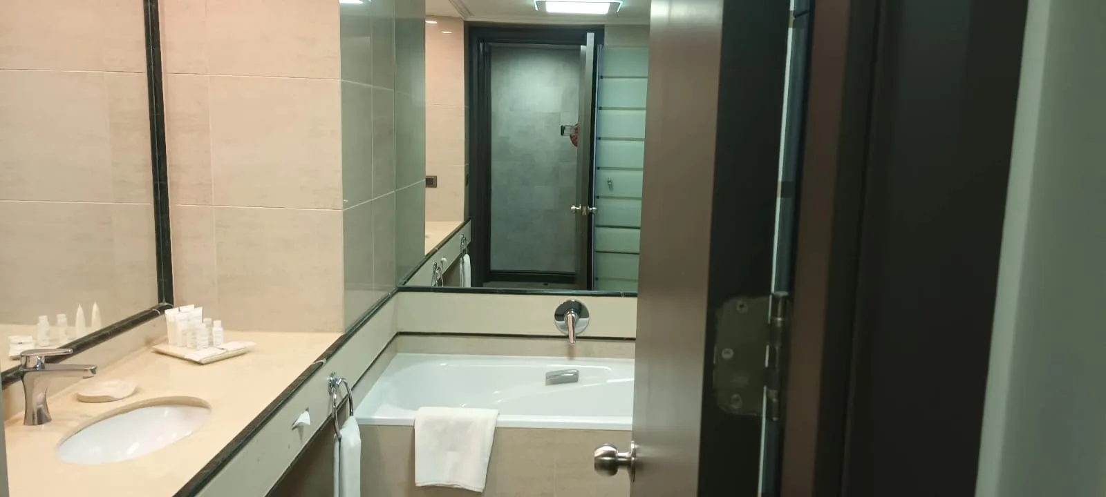 Hotelbad mit Waschbecken, Spiegel und Handtuch auf Badewanne