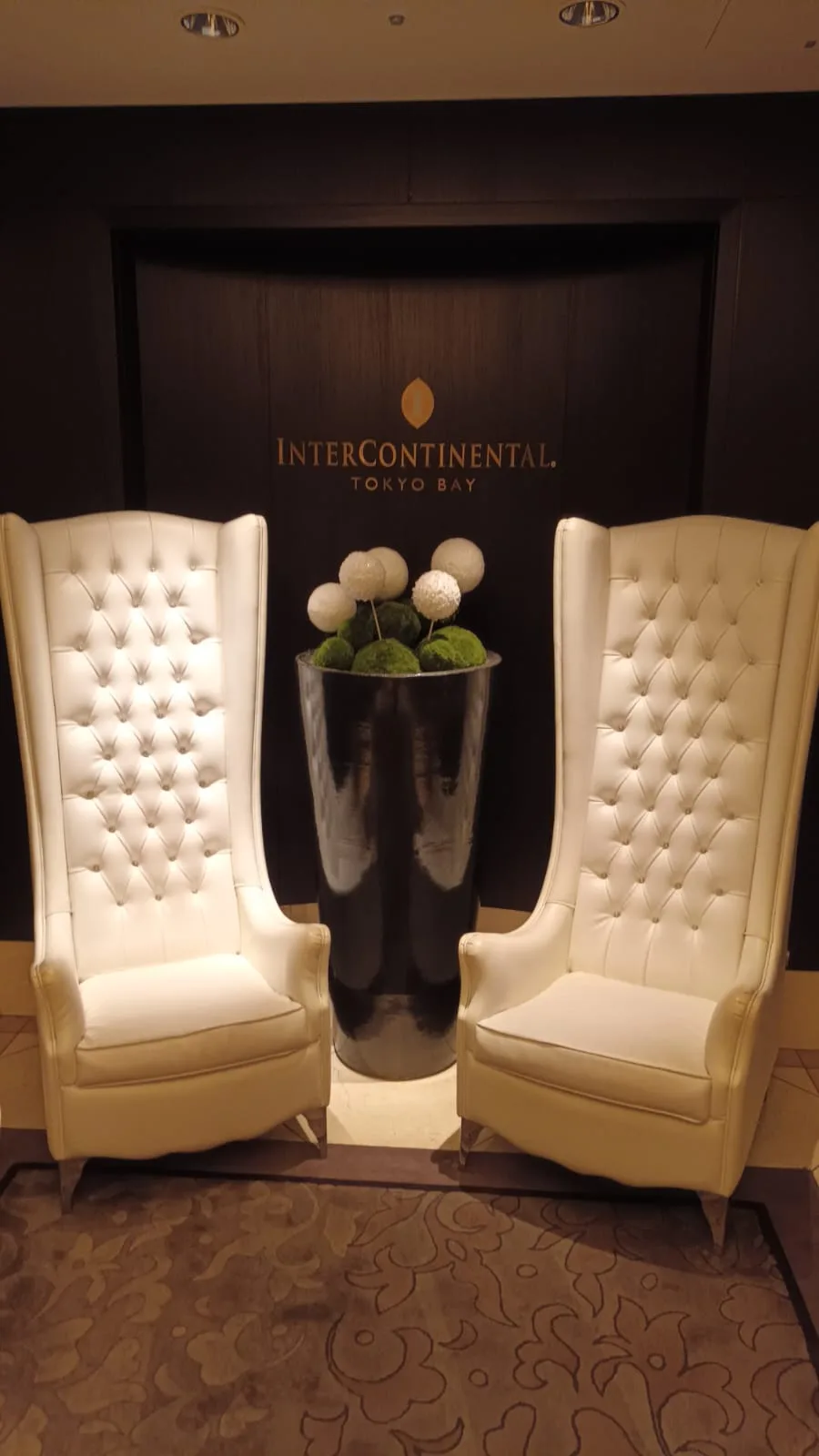 Zwei hohe weiße Sessel vor einem Eingang mit InterContinental Tokyo Bay-Schild