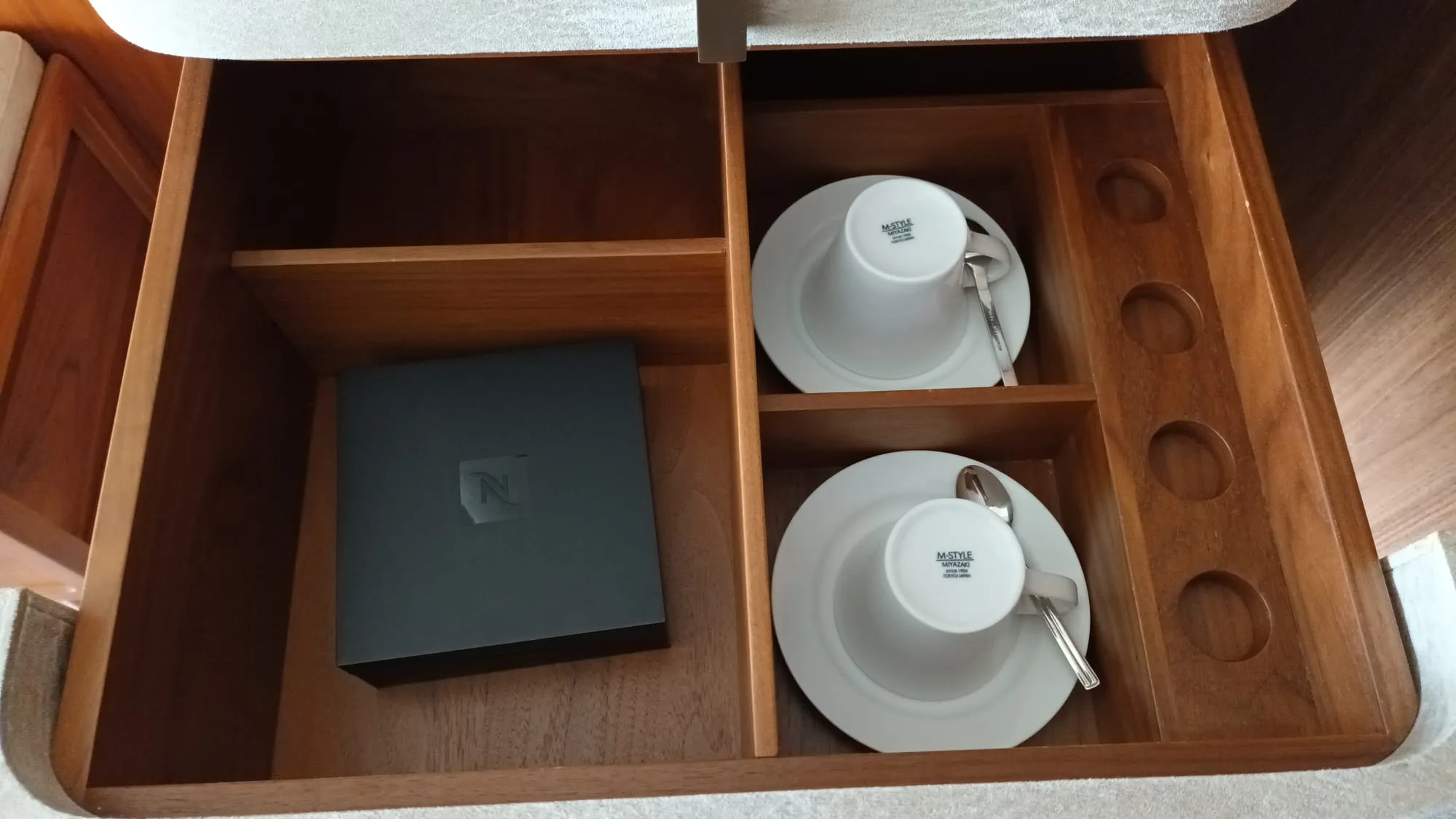 Holzschublade mit Kaffeetassen und Nespresso-Box