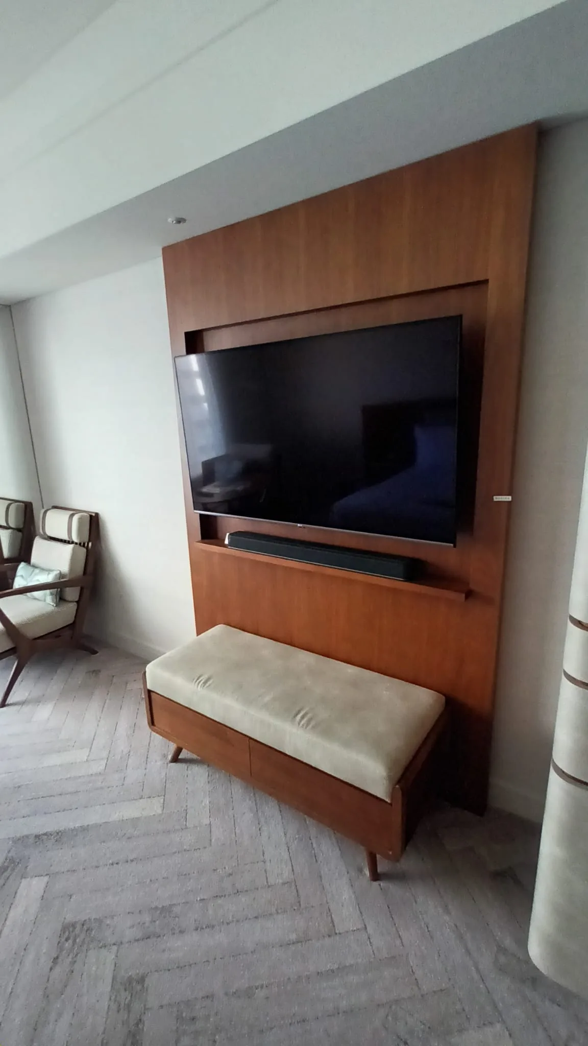 Holzverkleidete TV-Wand mit Sitzbank im Hotelzimmer