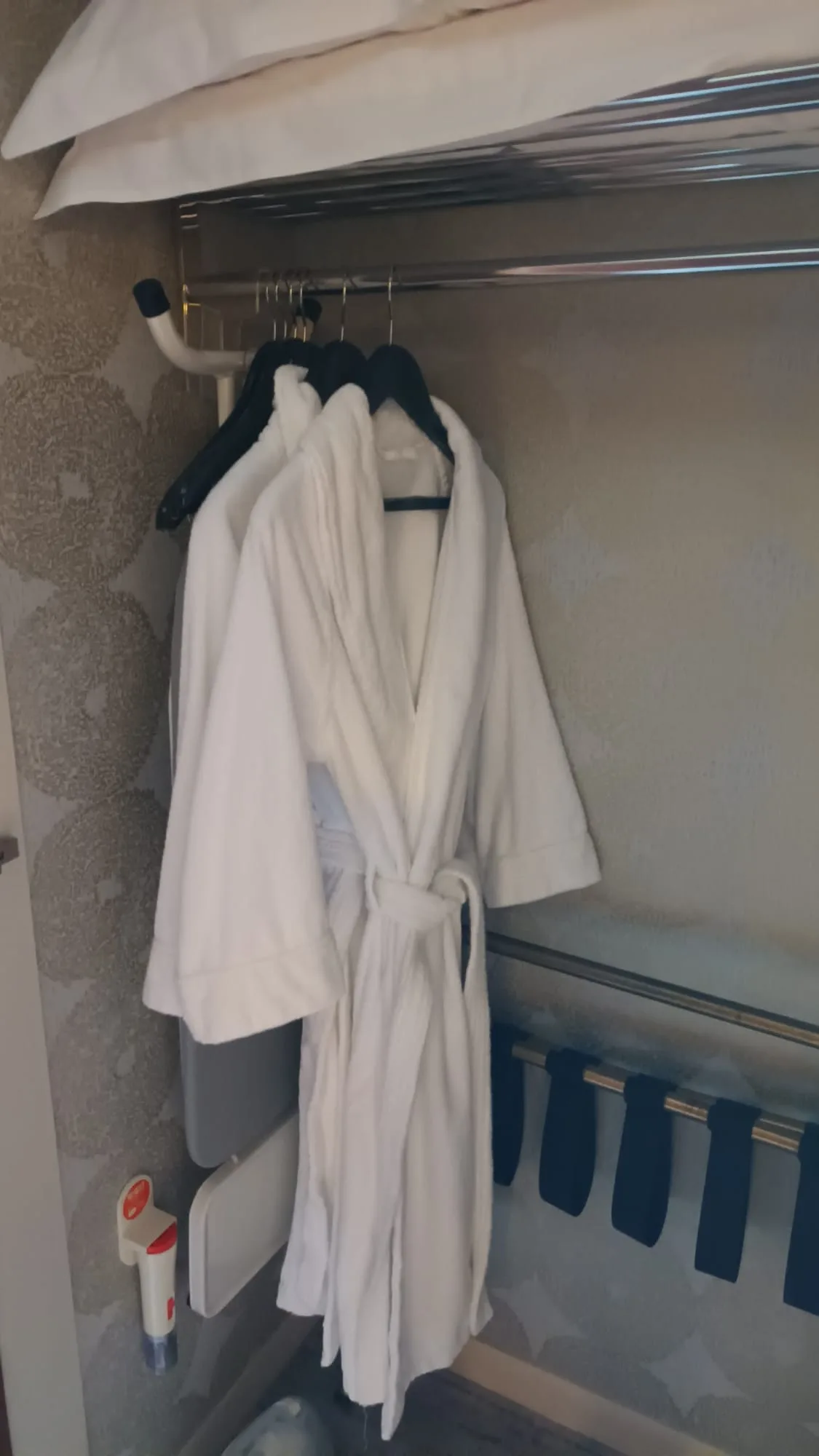 Weißer Bademantel hängt an Garderobe im Hotelzimmer