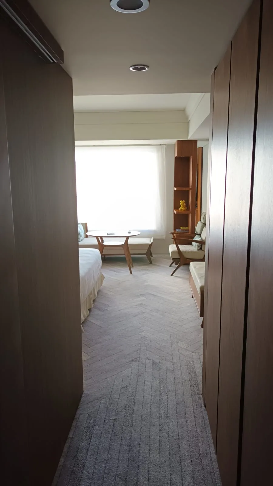 Hotelzimmer mit Doppelbett und Tagesdecke in Grautönen