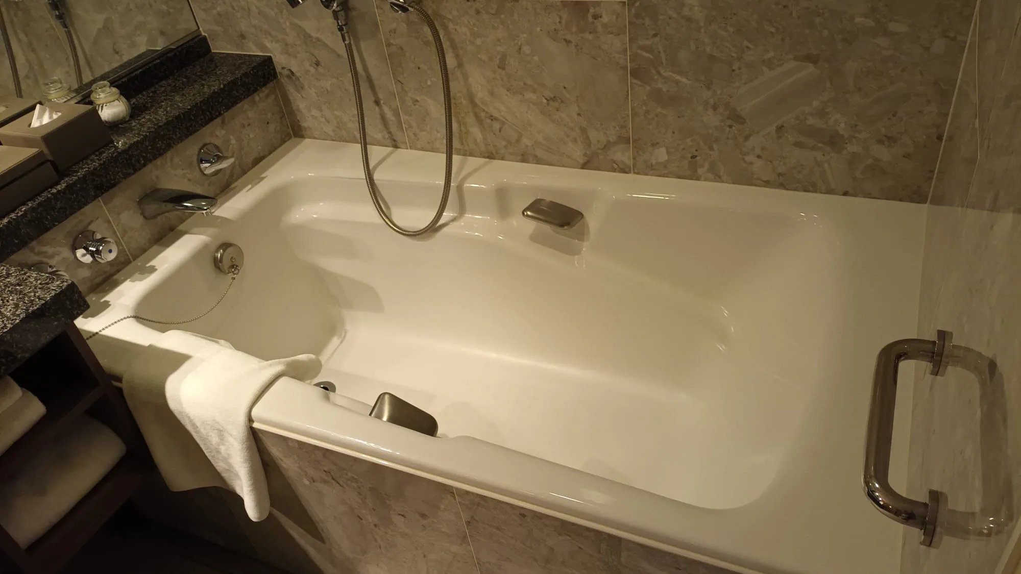 Weißer Badewannenbereich mit Handtuch und Griffen