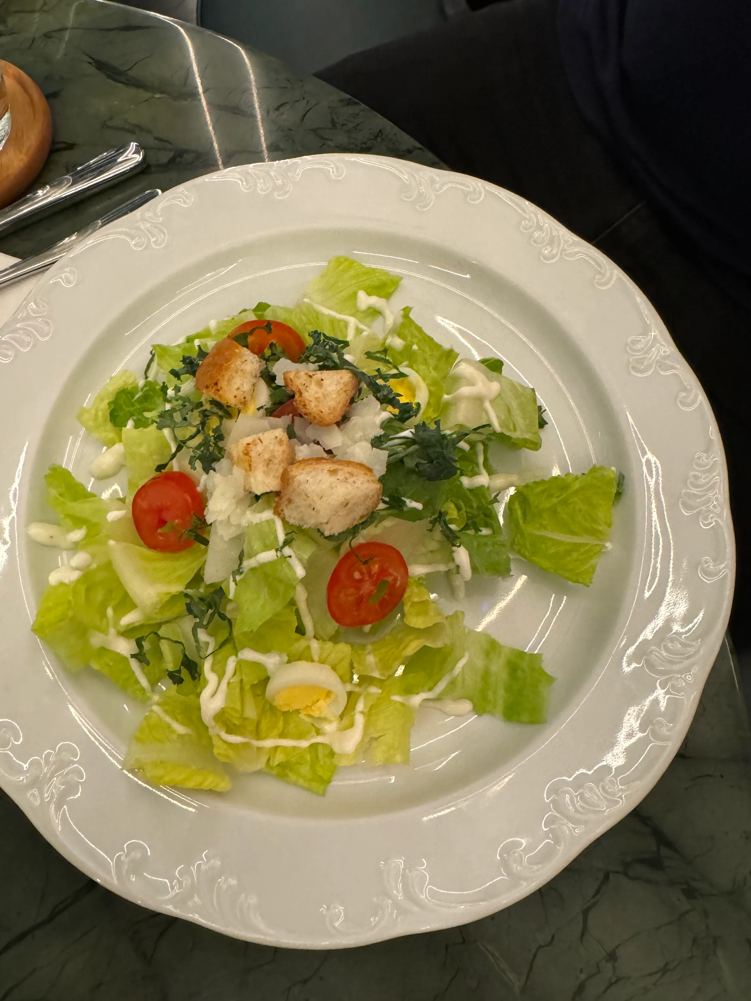 Caesar-Salat auf weißem Teller mit Kräutern und Tomaten