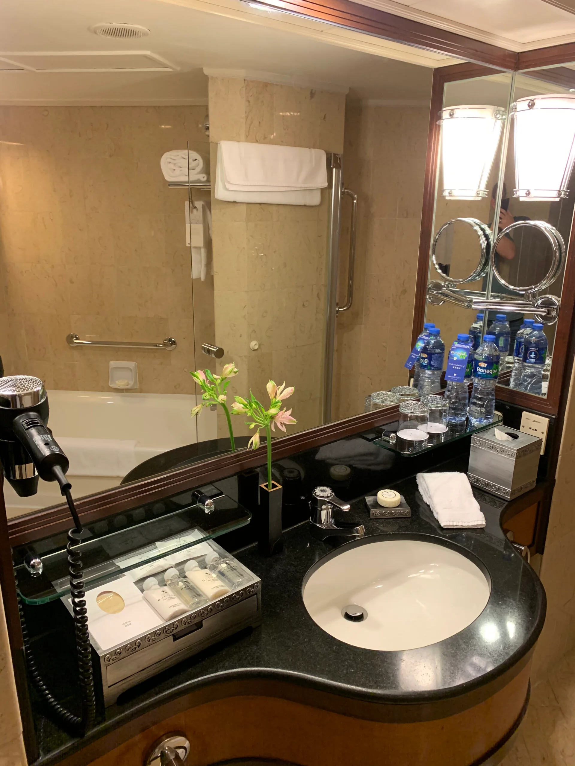Hotelbadezimmer mit Waschbecken, Spiegel und Flaschenwasser