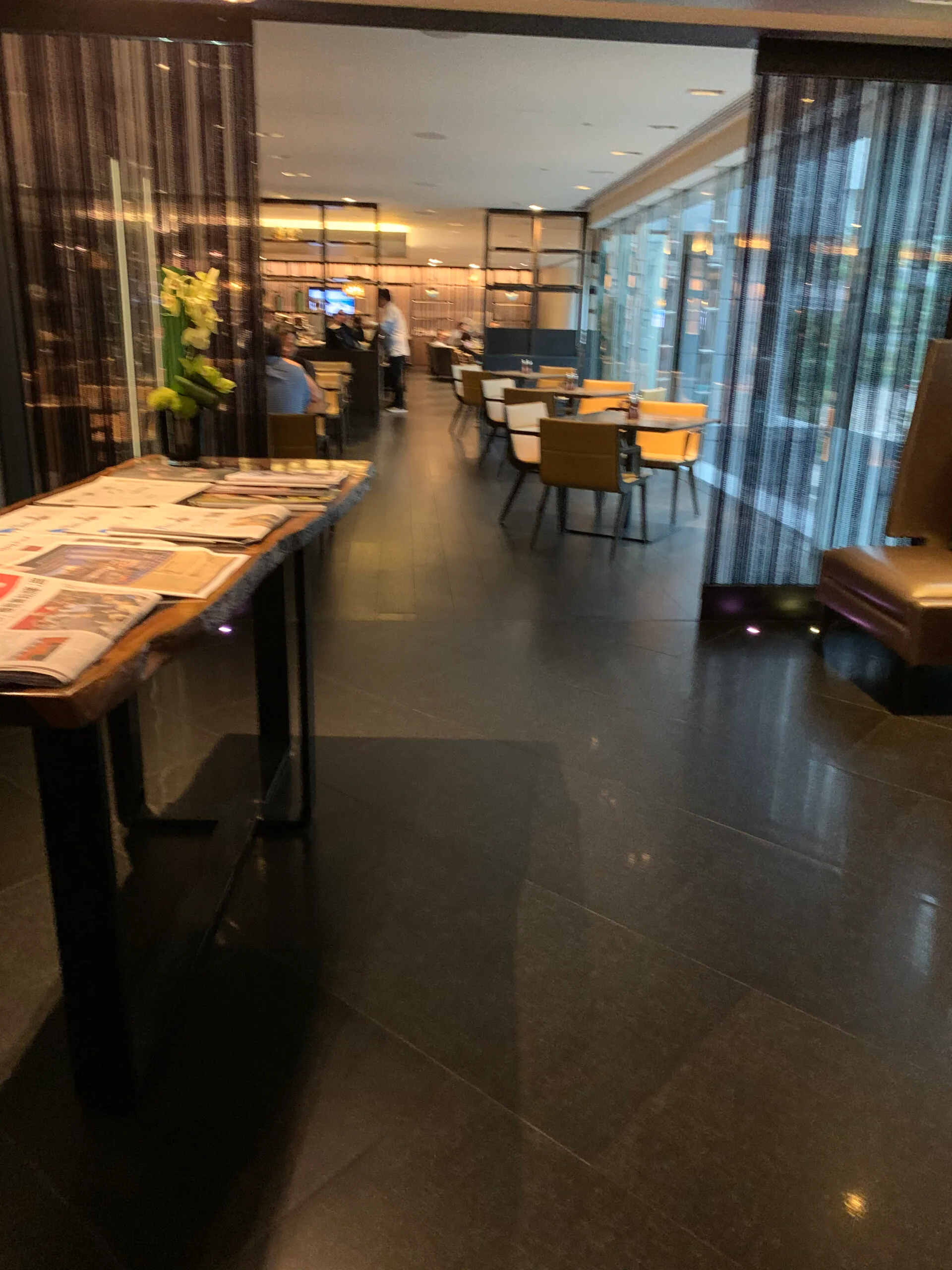 Hotellobby mit Zeitungen auf Tisch und Sesseln im Hintergrund