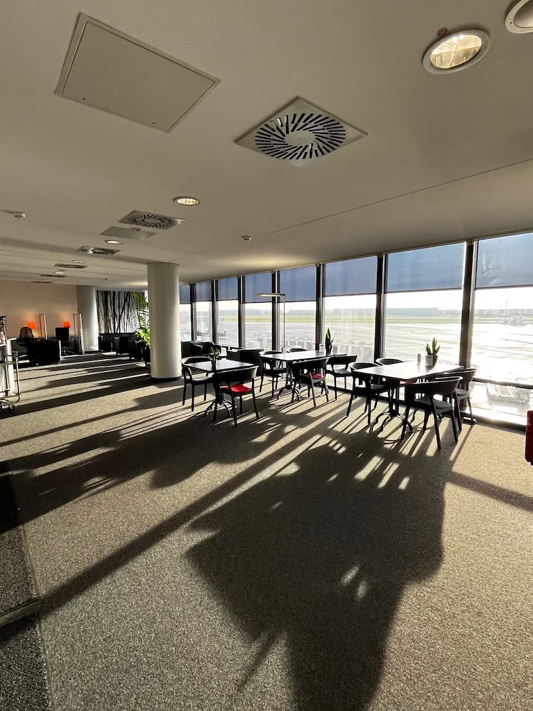 Lounge mit Tischen und Stühlen, Blick auf Flugfeld