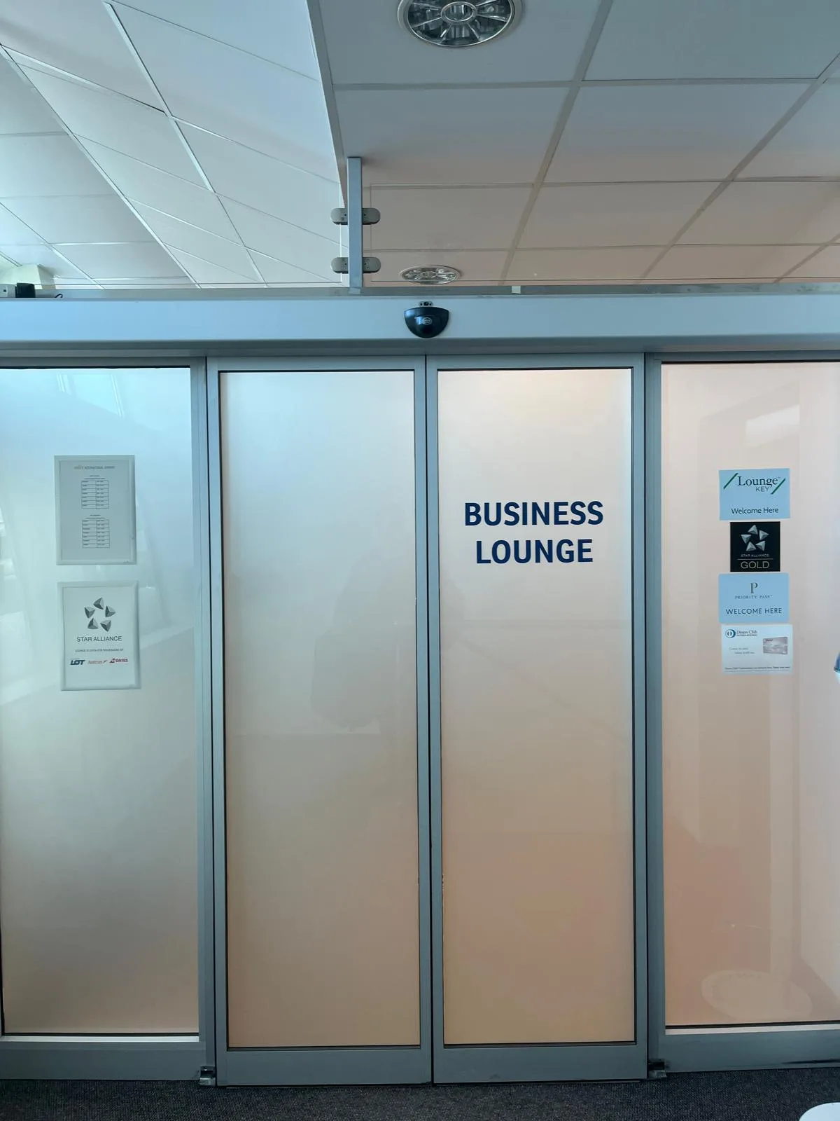 Glastür mit Schild 'Business Lounge' in einem Flughafen.