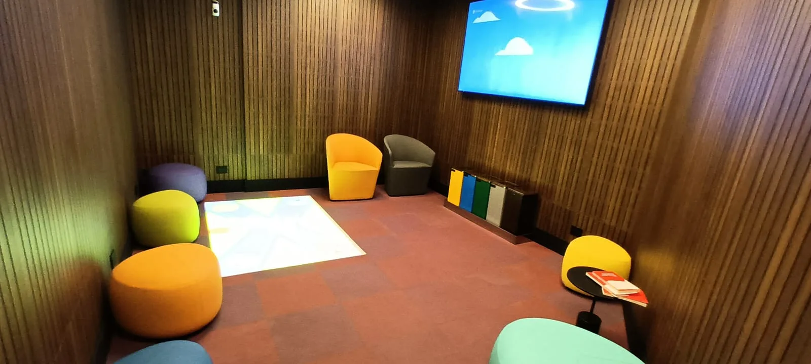 Kinderzimmer mit bunten Sitzmöbeln und Bildschirm
