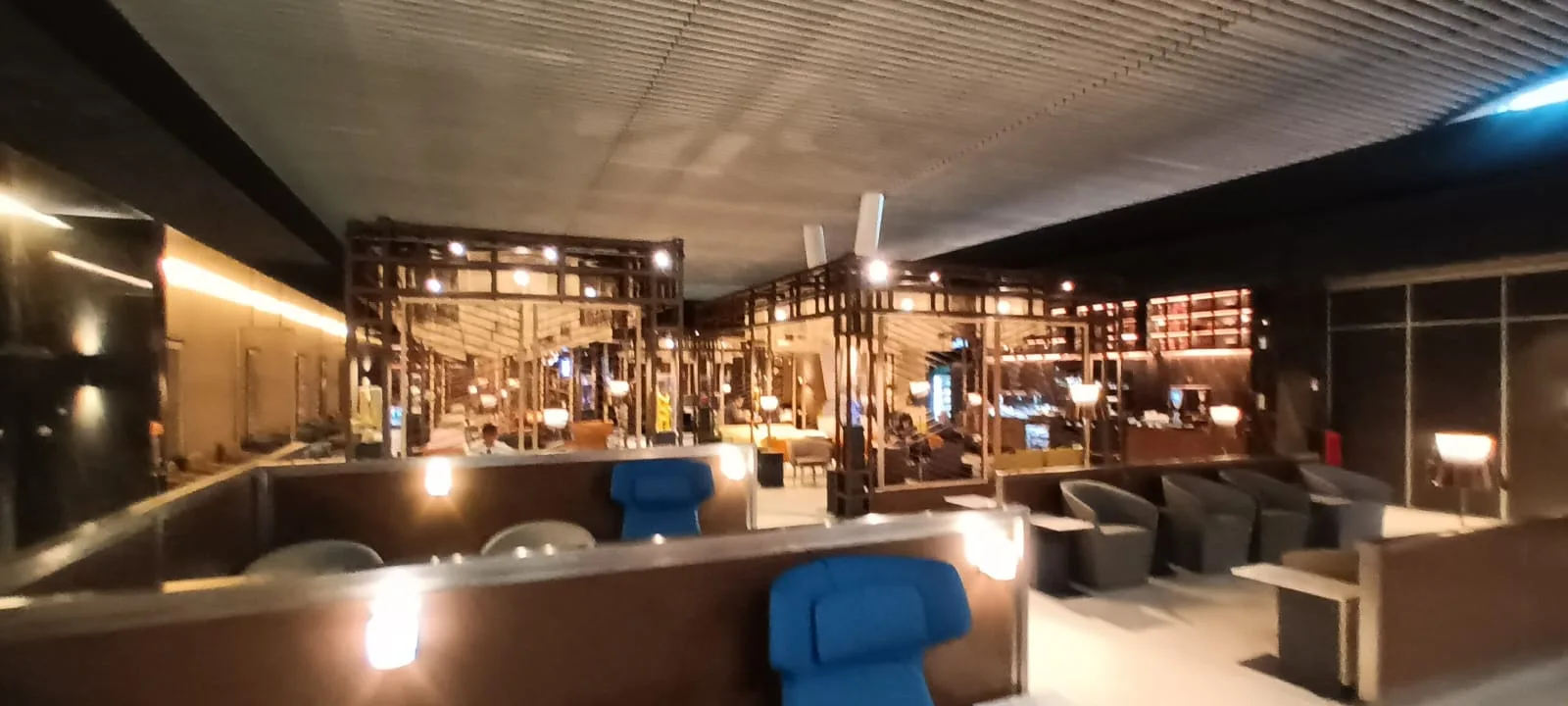 Lounge mit blauen Sesseln und Holzgestellen im Hintergrund
