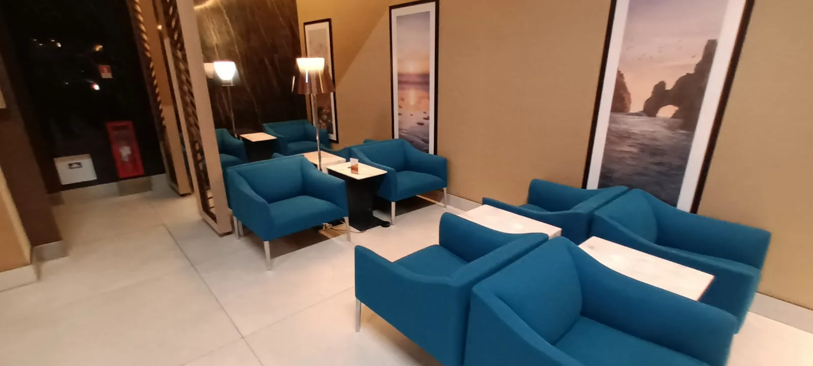 Blauer Sessel im Loungebereich mit Tischen und Wandbildern