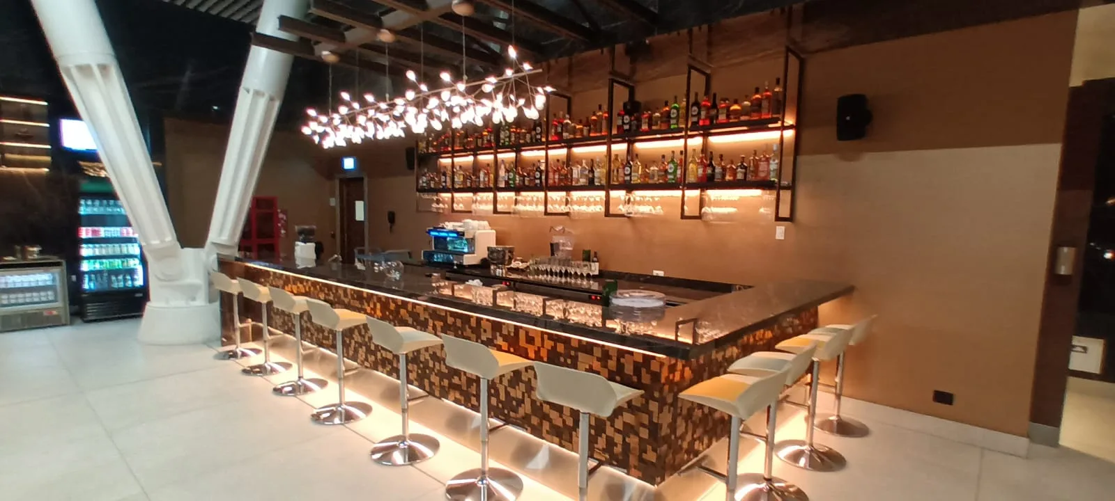 Bar mit Stühlen und Flaschenregalen im Loungebereich