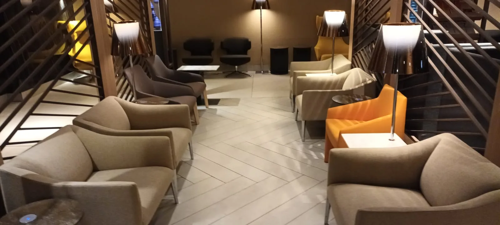 Lounge mit Sesseln und Stehlampen in warmen Farbtönen