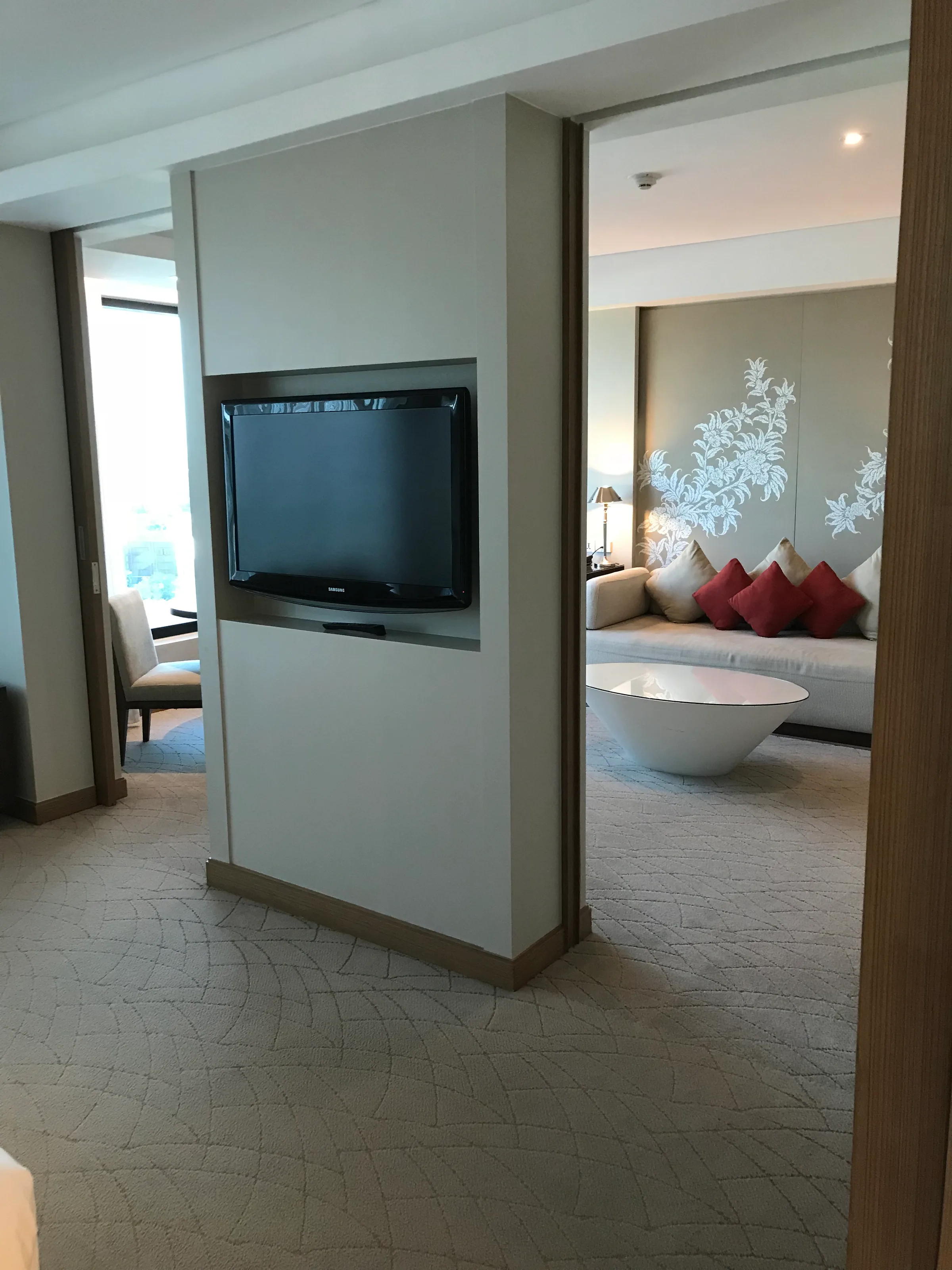 Hotelzimmer mit eingebautem Fernseher und Couch im Hintergrund
