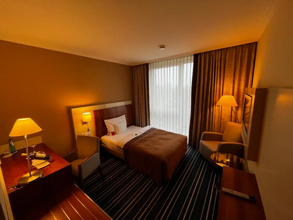 Hotelzimmer mit Doppelbett und Tagesdecke in Grautönen