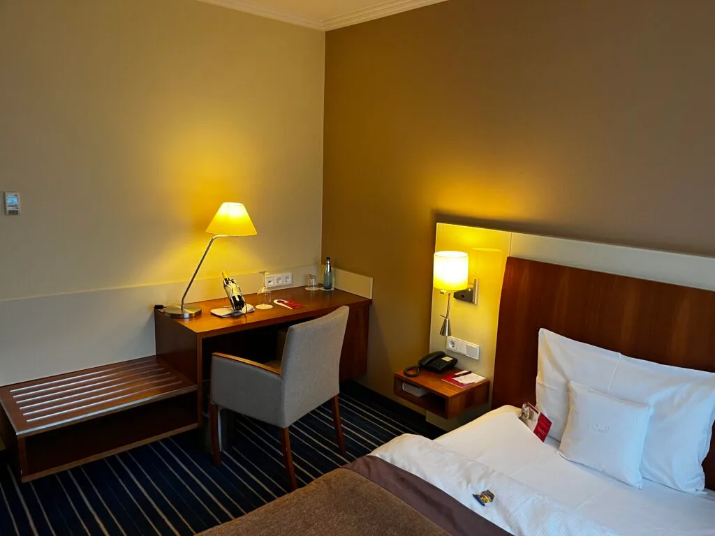 Hotelzimmer mit Doppelbett und Schreibtisch in warmen Farbtönen