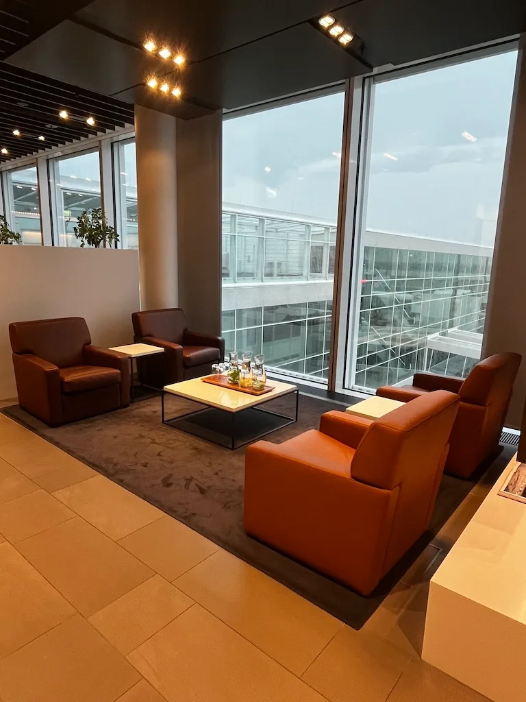 Lounge mit Sesseln und Couch vor großem Fenster im Flughafen