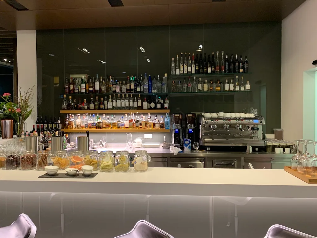Bar mit Flaschenregalen und Kaffeemaschine im First Class Lounge München