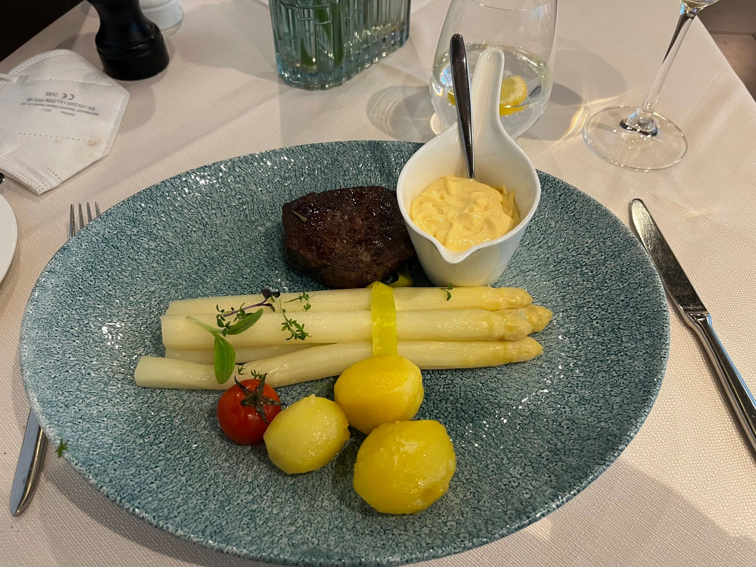 Gefülltes Steak mit Spargel und Sauce auf blauem Teller