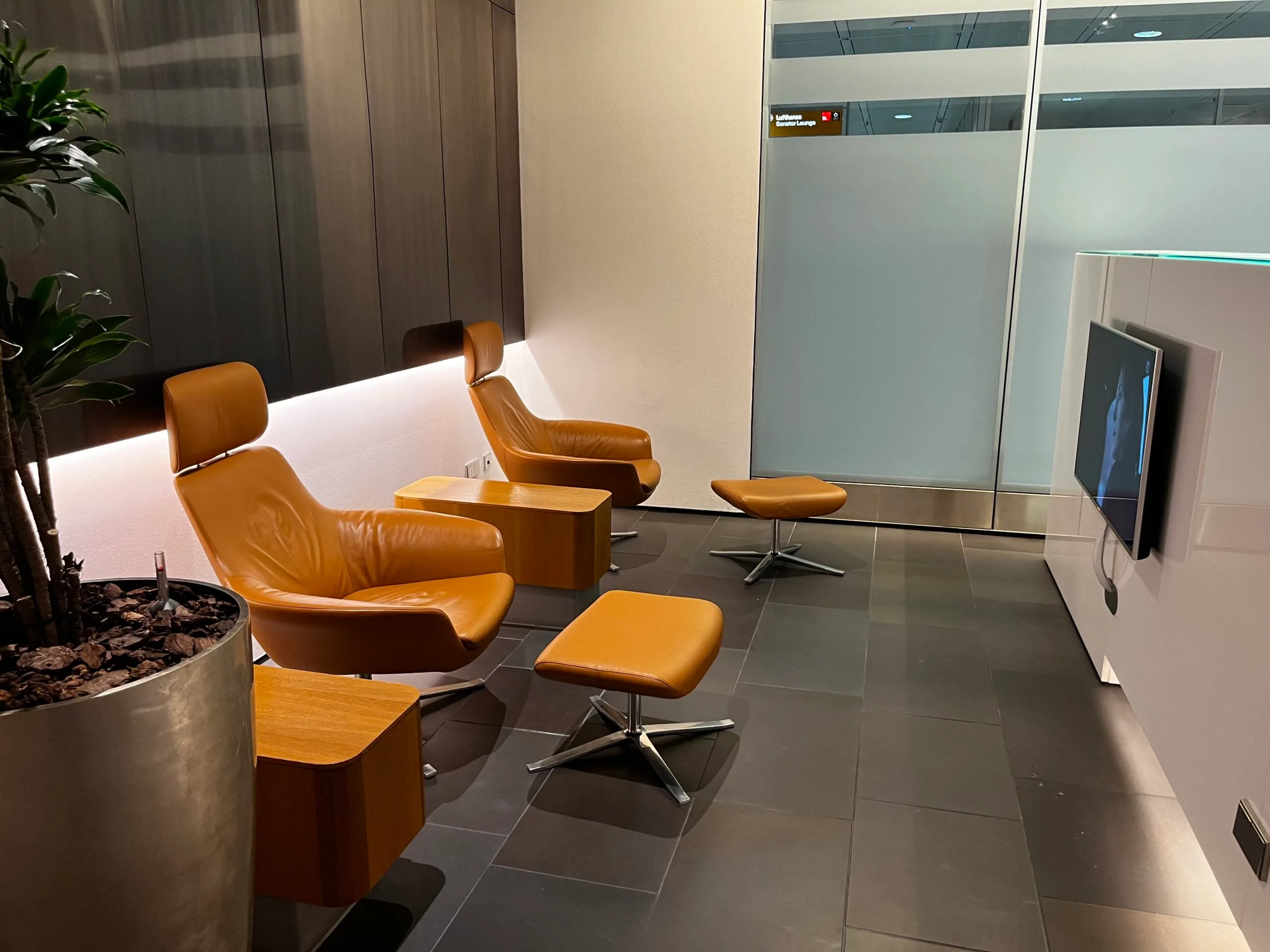 Lounge mit orangefarbenen Ledersesseln und Hocker vor Fernseher