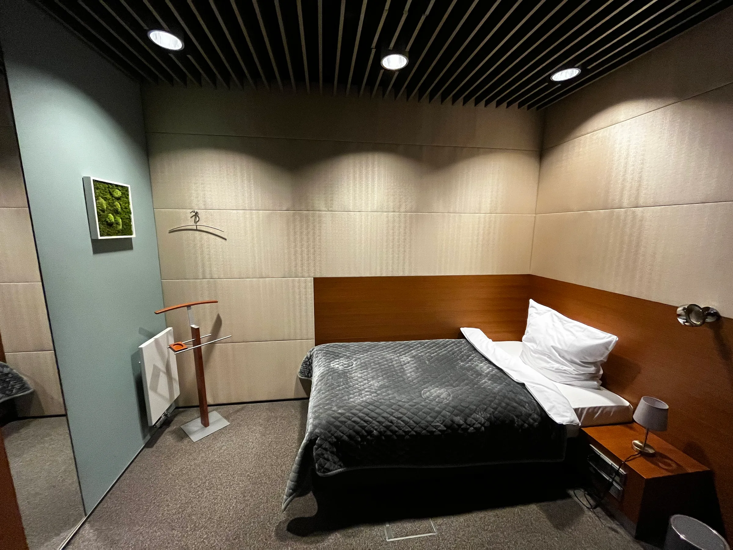 Hotelzimmer mit Doppelbett und grauem Tagesdeckenbezug