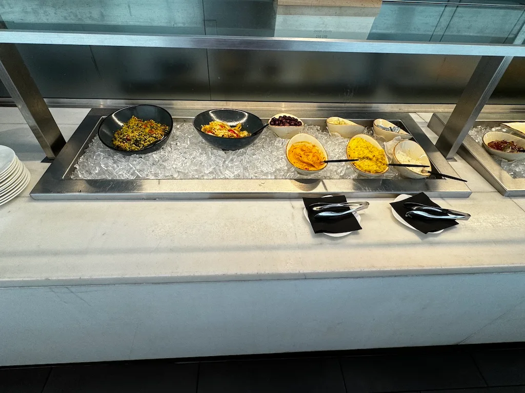 Reihen von Sesseln in einem Flughafen-Lounge mit grauem Teppich und Marmor-Tischplatten