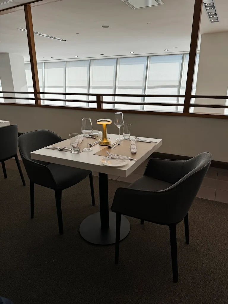 Gedeckter Tisch in First Class Lounge mit modernen Stühlen und großen Fenstern