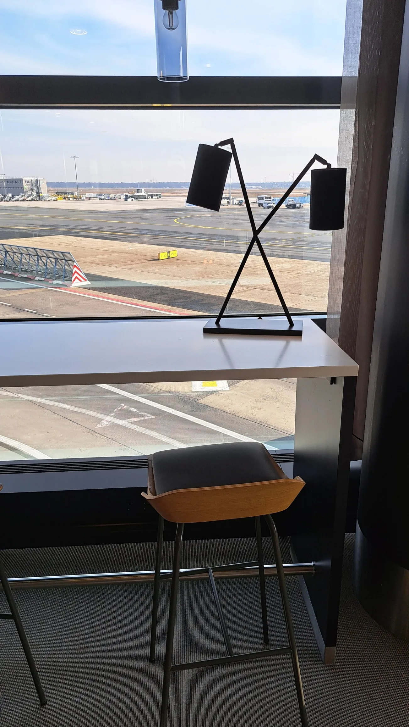 Tisch mit Stuhl und Lampe am Flughafenfenster