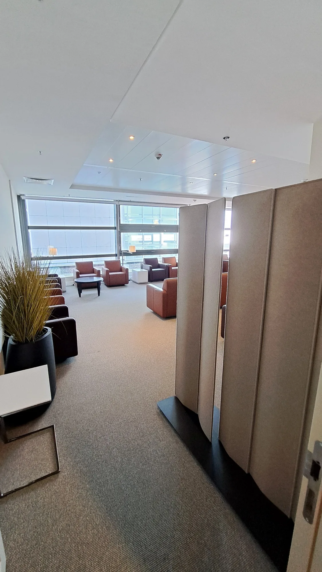 Panoramalounge mit Sesseln und Tischen vor Fenster