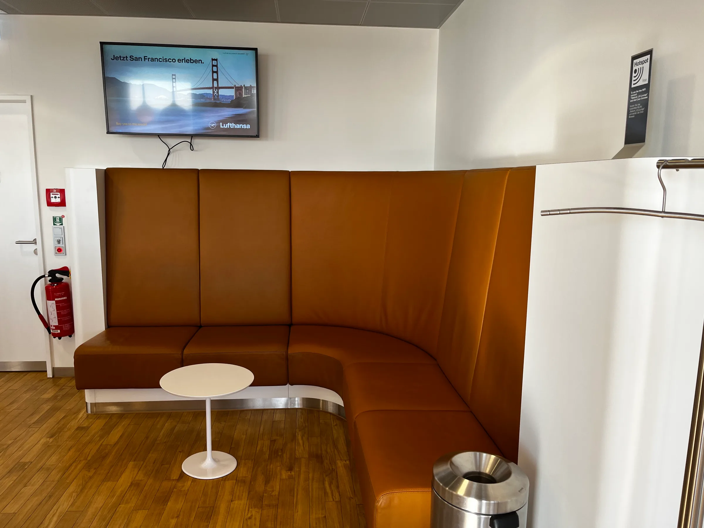 Lounge mit orangefarbenen Sitzmöbeln und Fernseher
