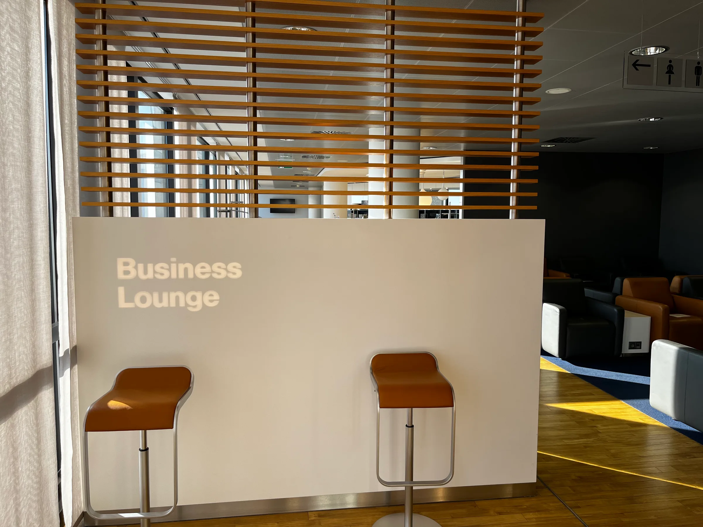 Business Lounge mit Sitzhockern und Holzjalousien
