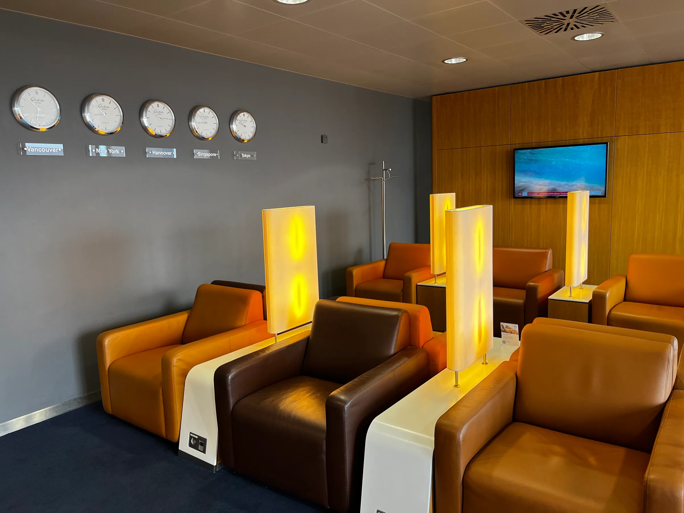 Lounge mit Sesseln und Uhrzeitzonen an der Wand