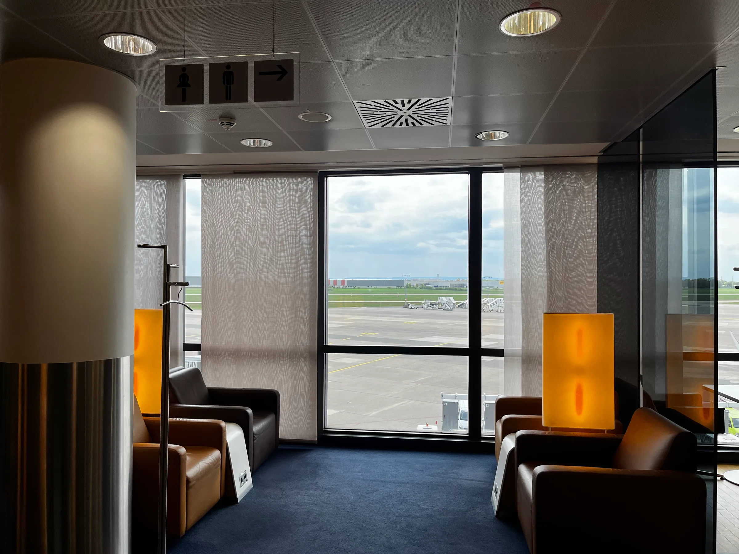 Lounge mit Sesseln und Fensterblick auf Flughafen