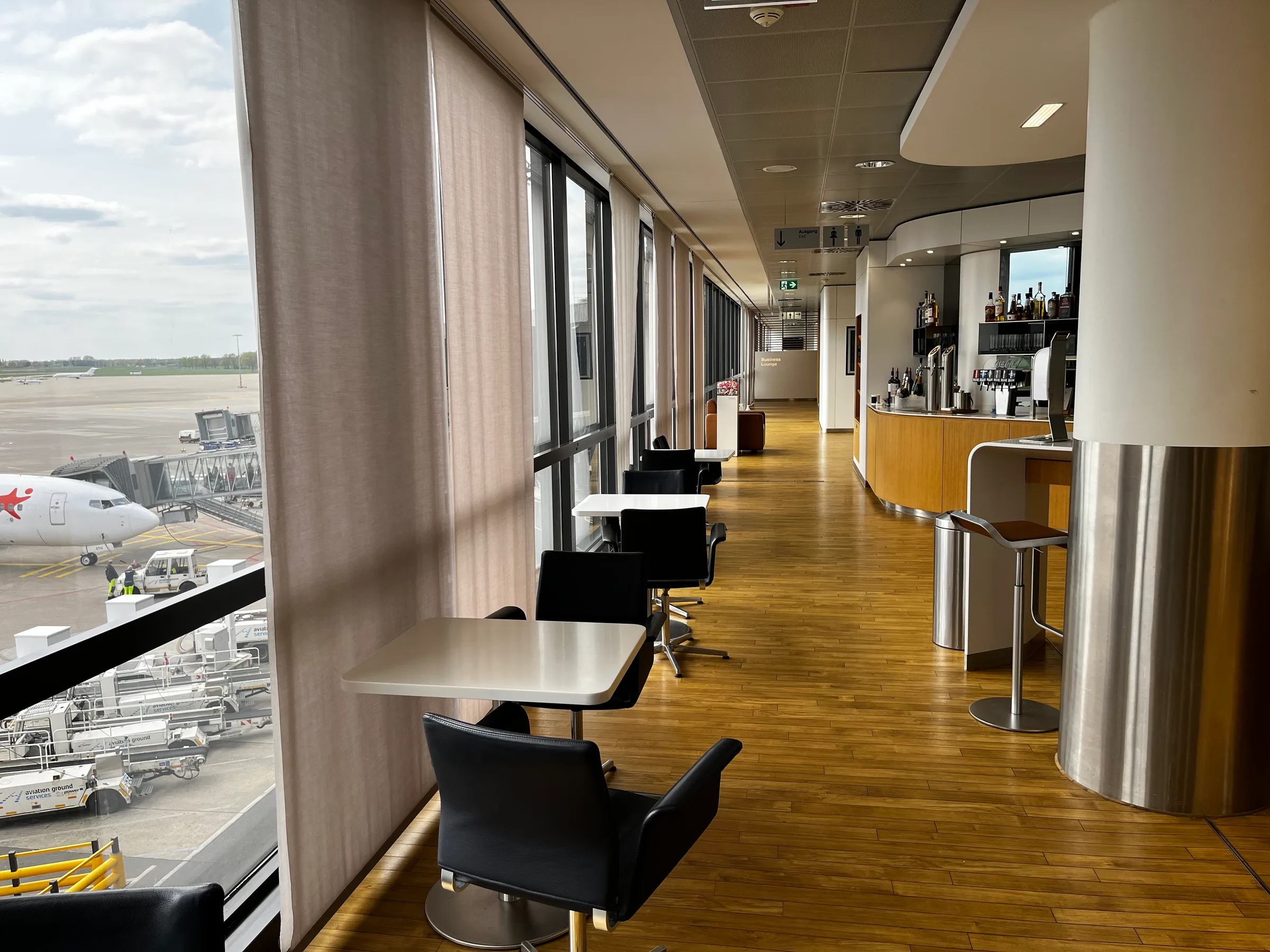 Lounge mit Tischen und Stühlen am Flughafenfenster