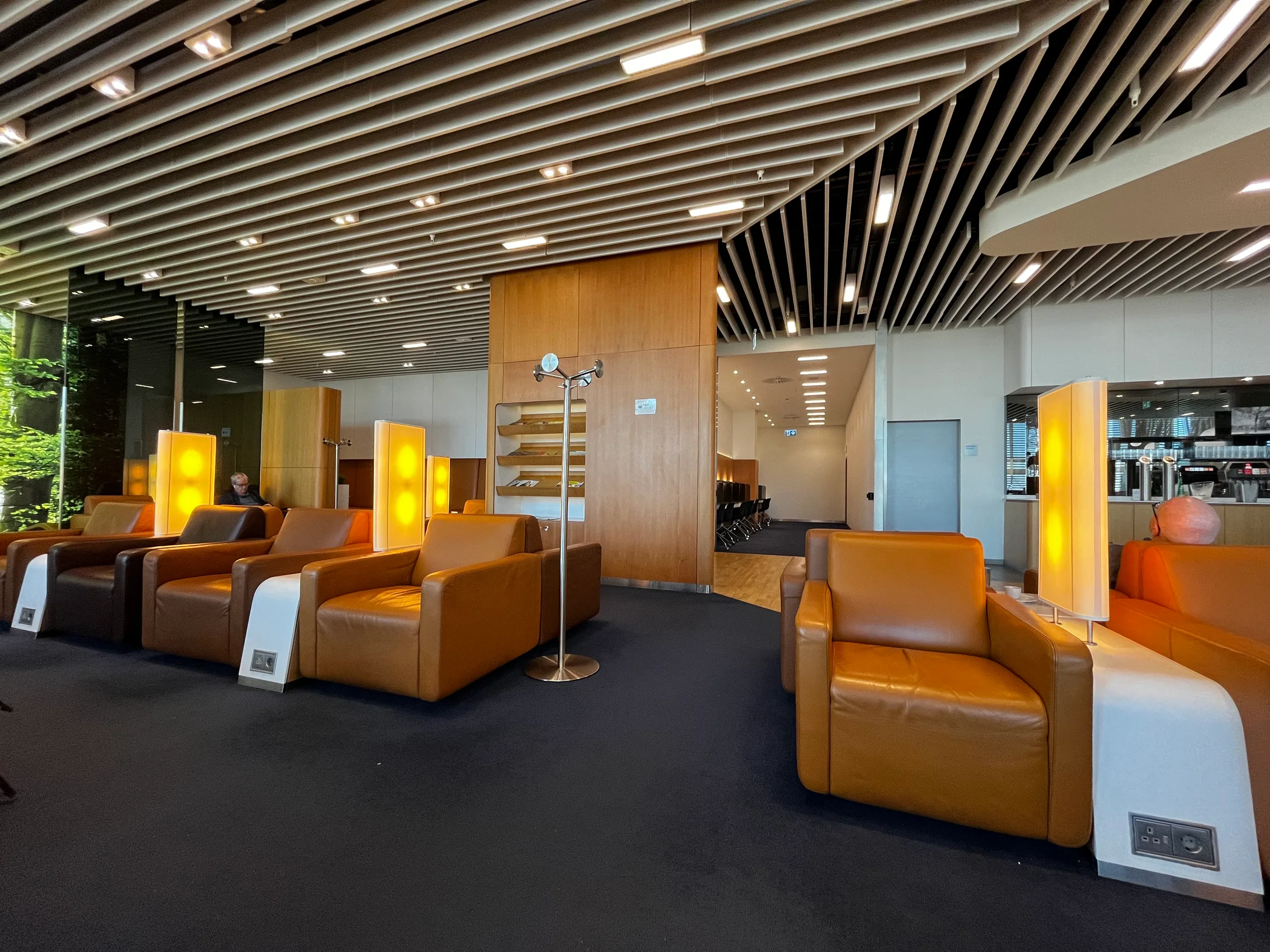 Lounge mit orangefarbenen Ledersesseln und moderner Holzdecke