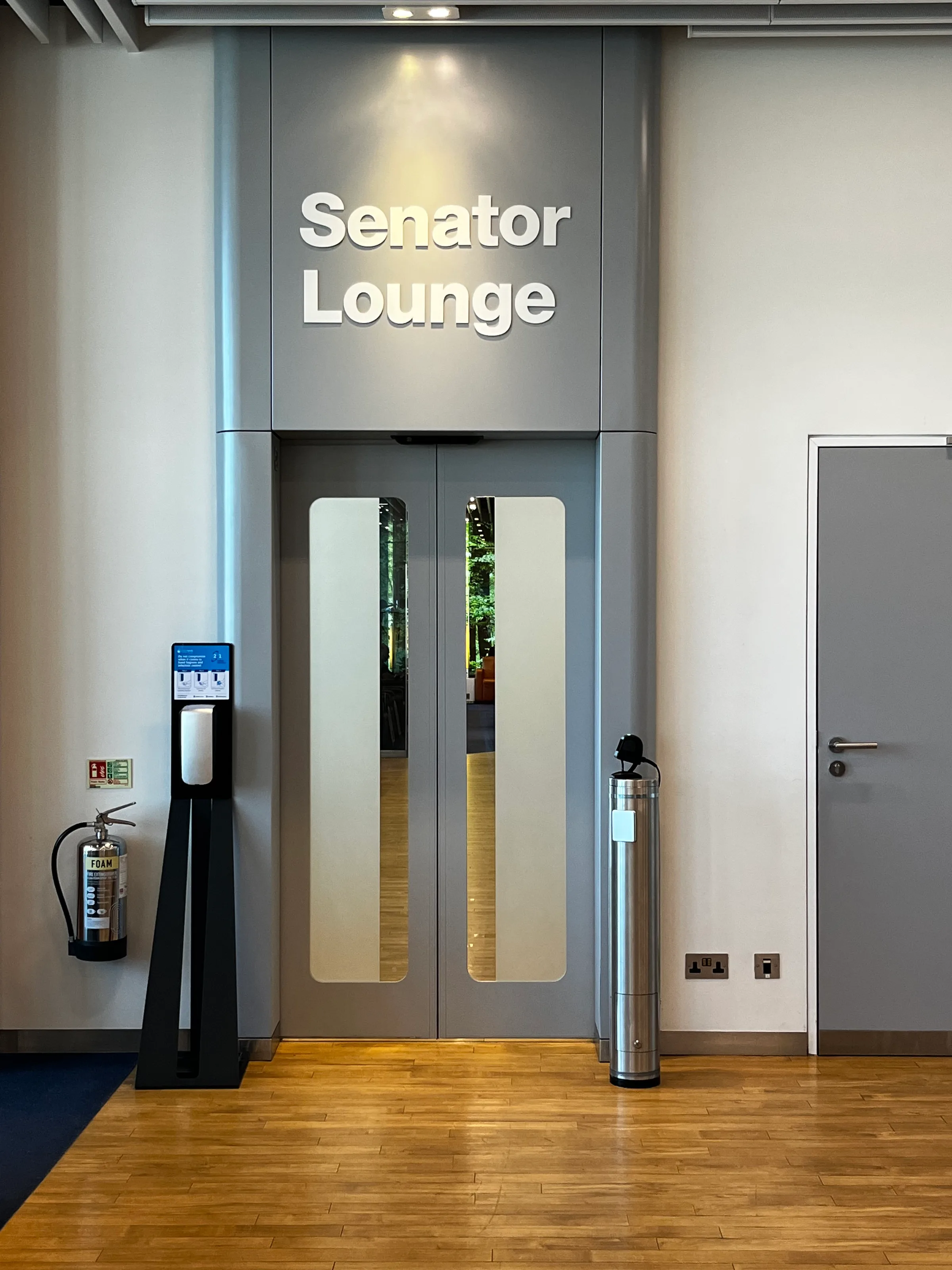 Eingang zur Senator Lounge mit Schild und automatischem Händedesinfektionsautomat