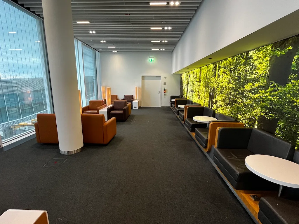 Lounge mit Sesseln und Tischen vor Panoramafenster