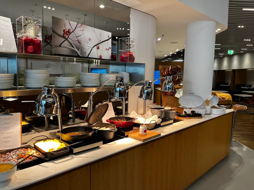 Buffet mit verschiedenen Gerichten und Kochutensilien im Lufthansa Senator Lounge München