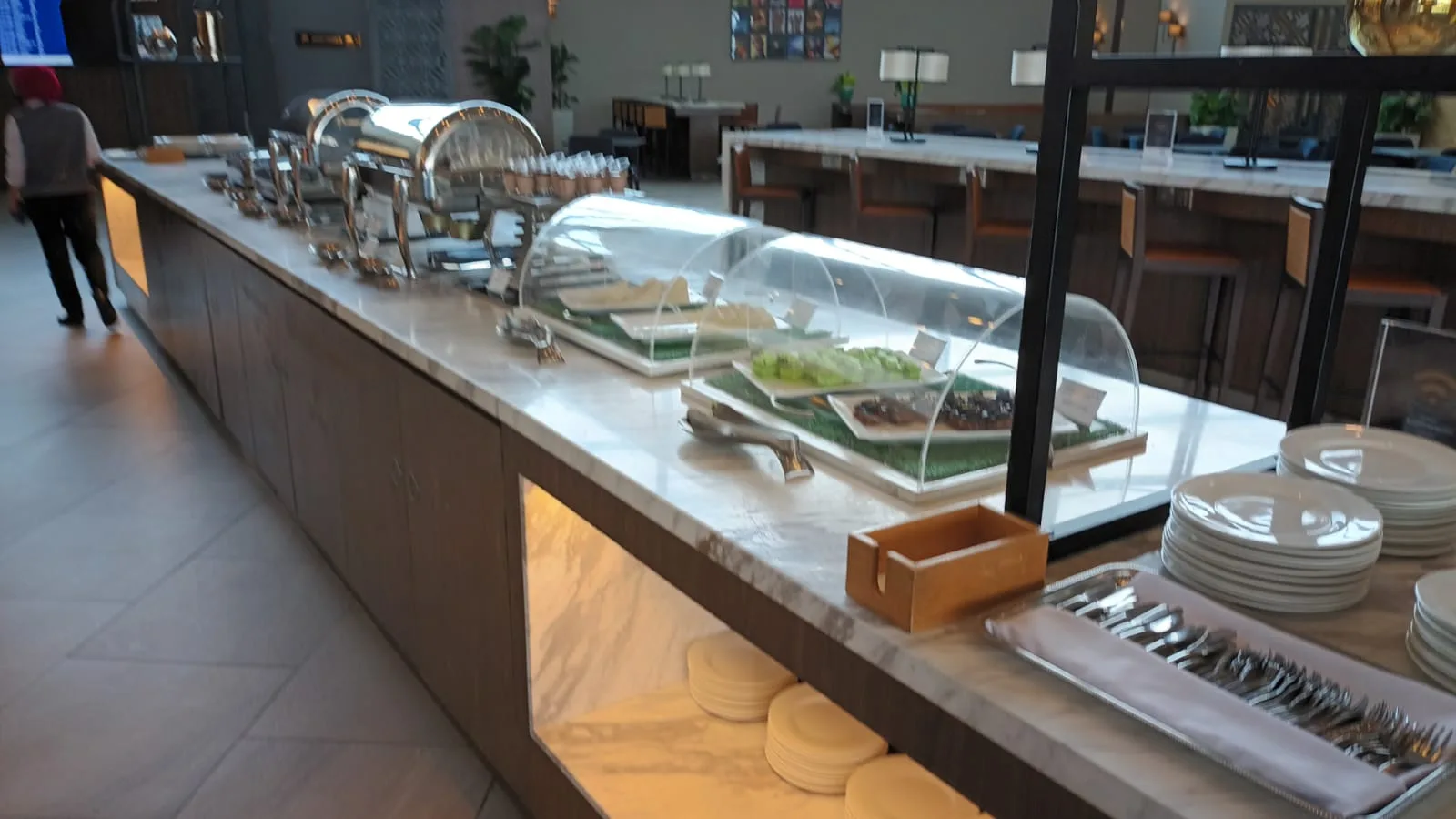 Buffet mit verschiedenen Speisen und Servierutensilien im Flughafenlounge