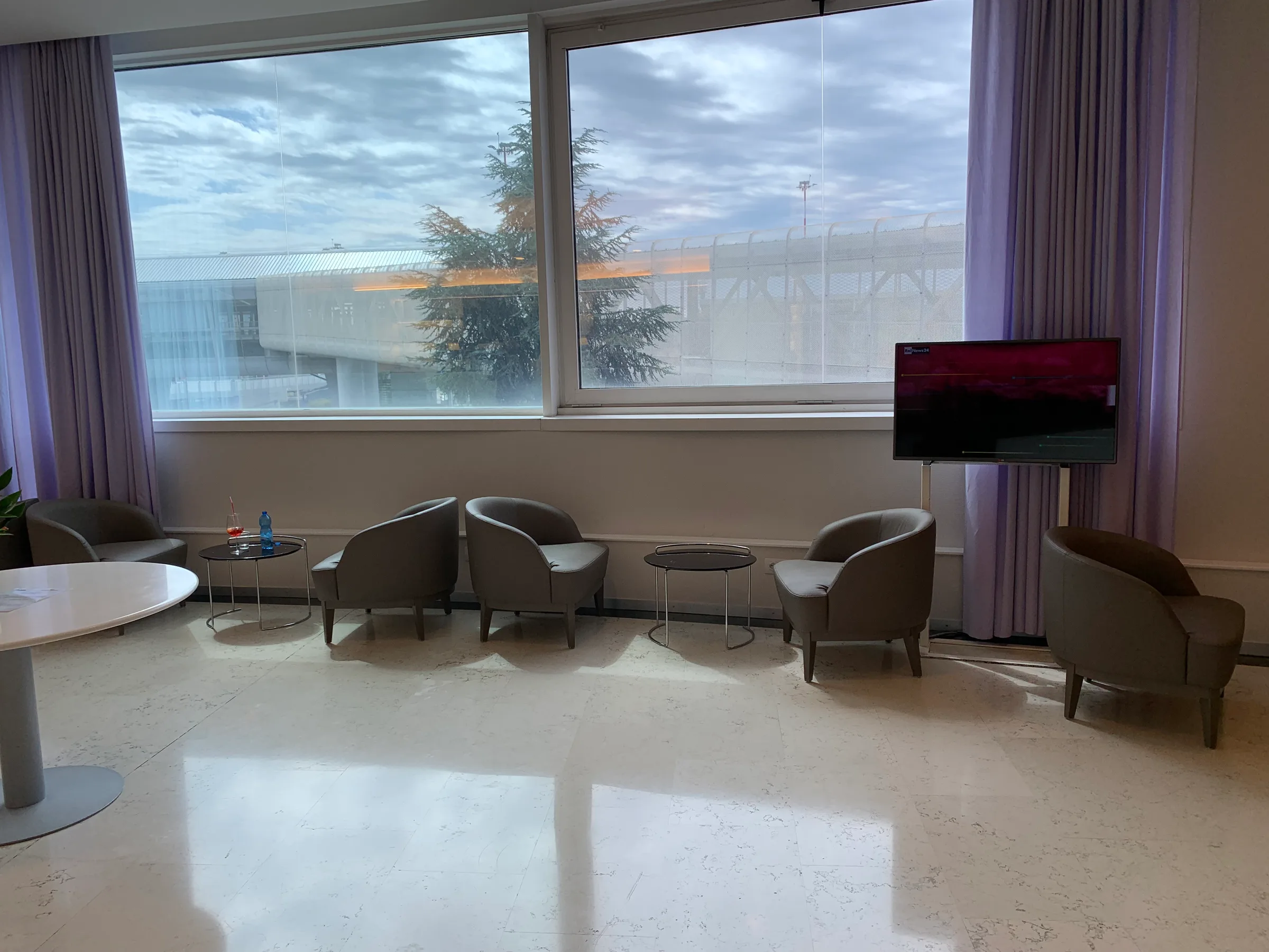 Businesslounge mit Sesseln und Fernseher vor Fenster