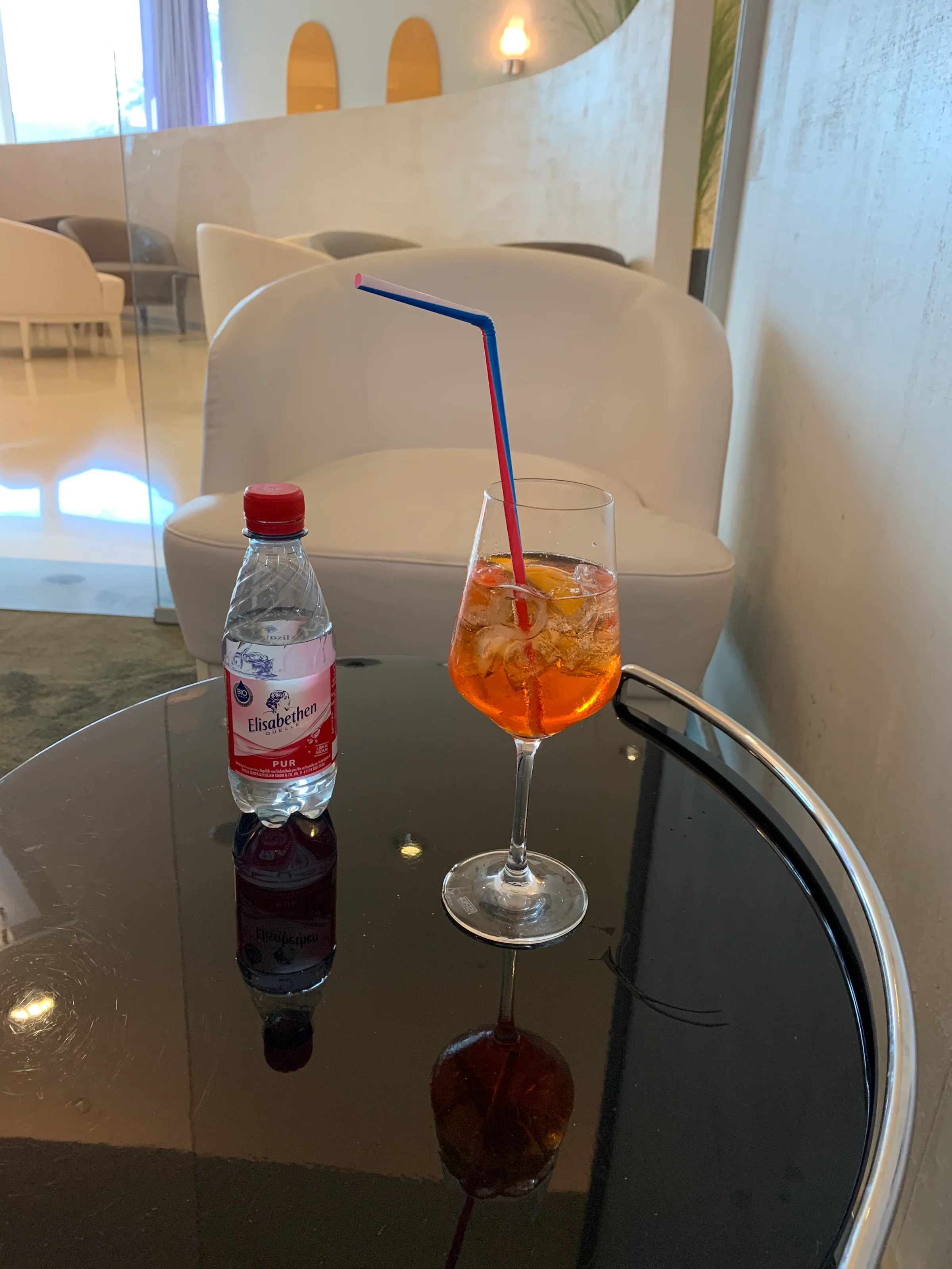 Glas mit Cocktail und Wasserflasche auf Couchtisch
