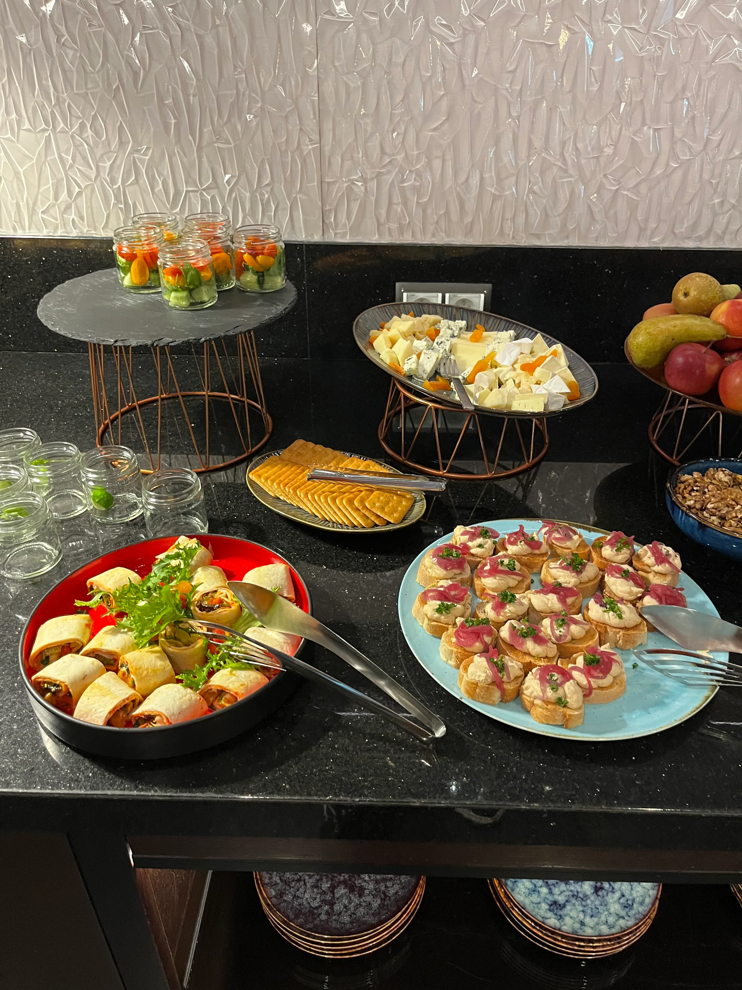 Buffet mit verschiedenen Snacks und Käse auf einem schwarzen Tisch