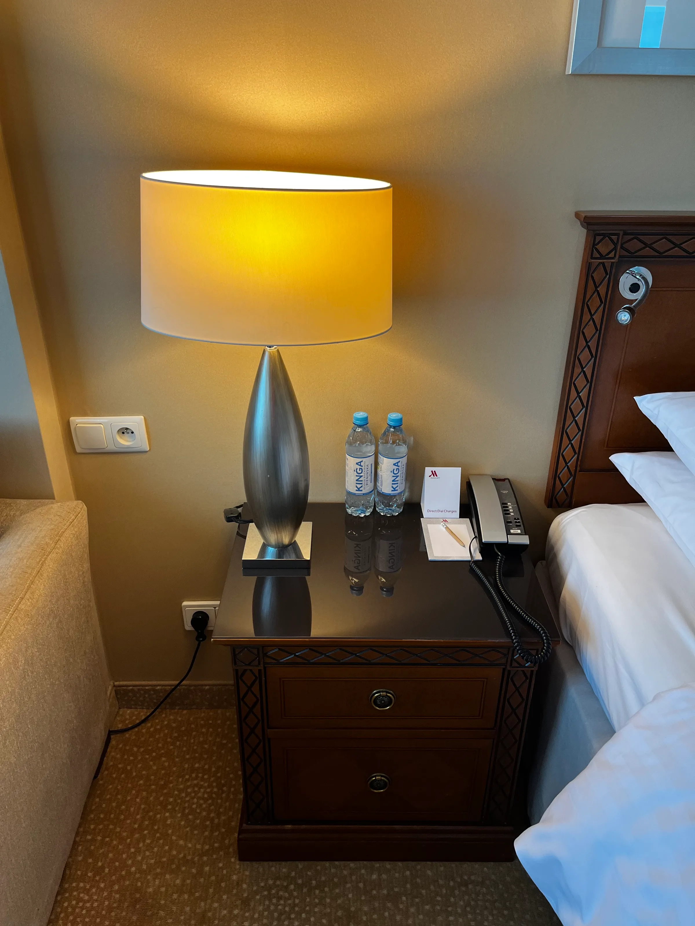 Hotelzimmer mit Nachttischlampe und Wasserflaschen