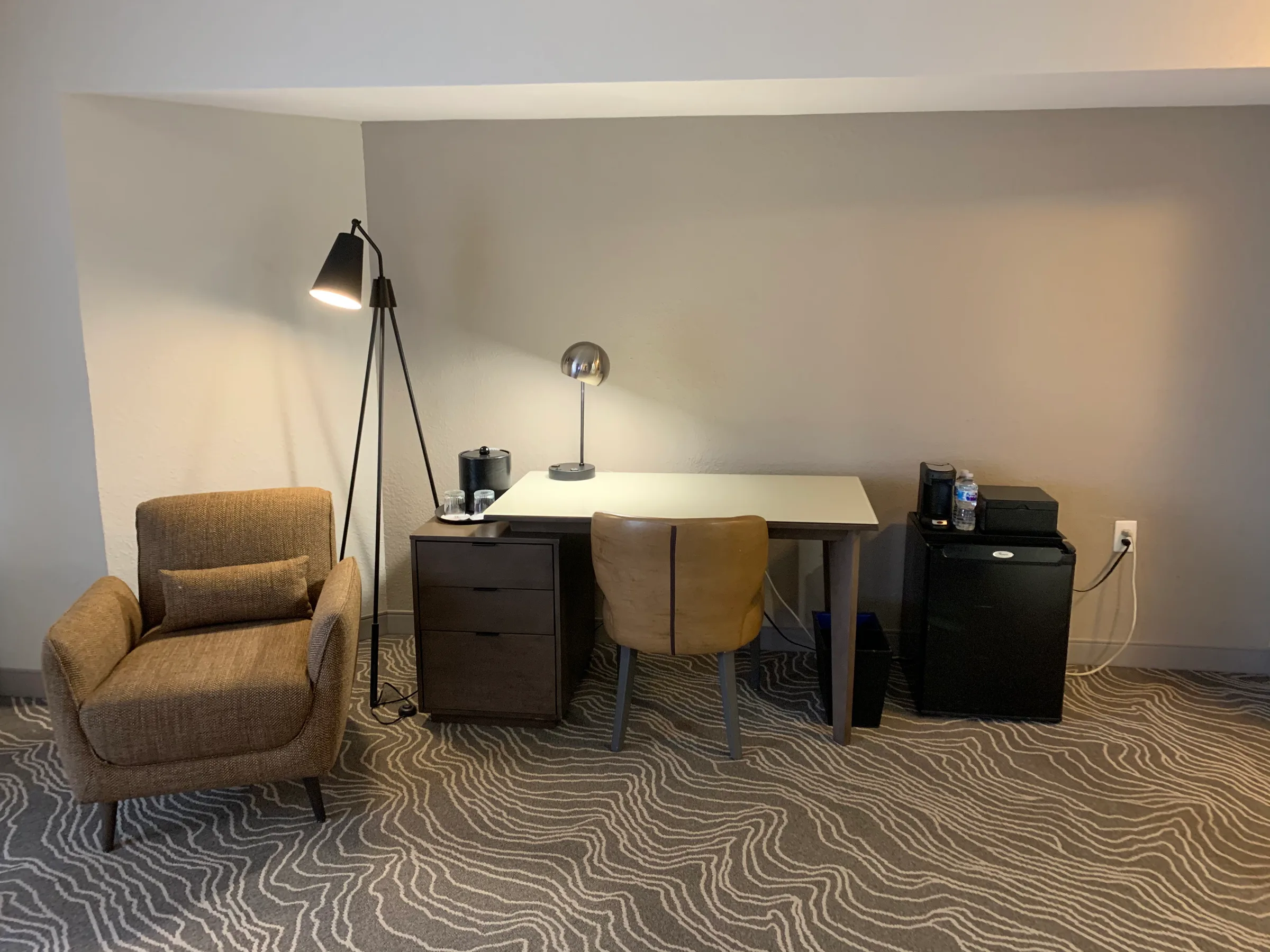Hotelzimmer mit Schreibtisch, Stuhl und Stehlampe