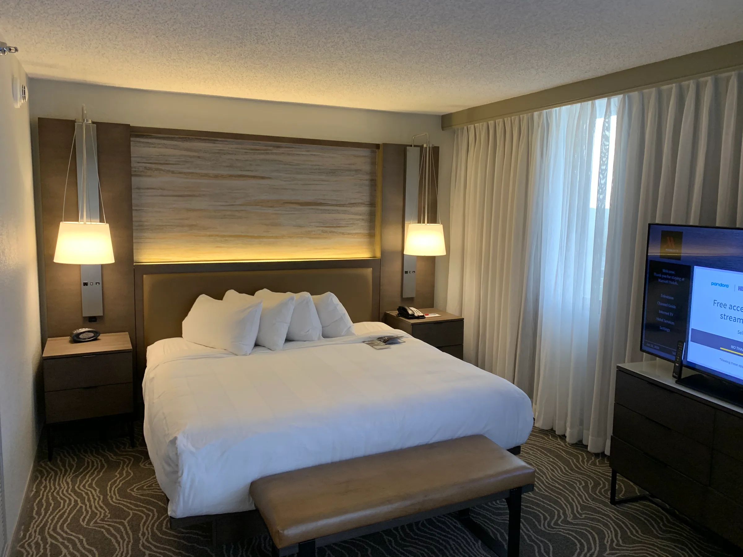 Hotelzimmer mit Doppelbett und Tagesdecke in Grautönen