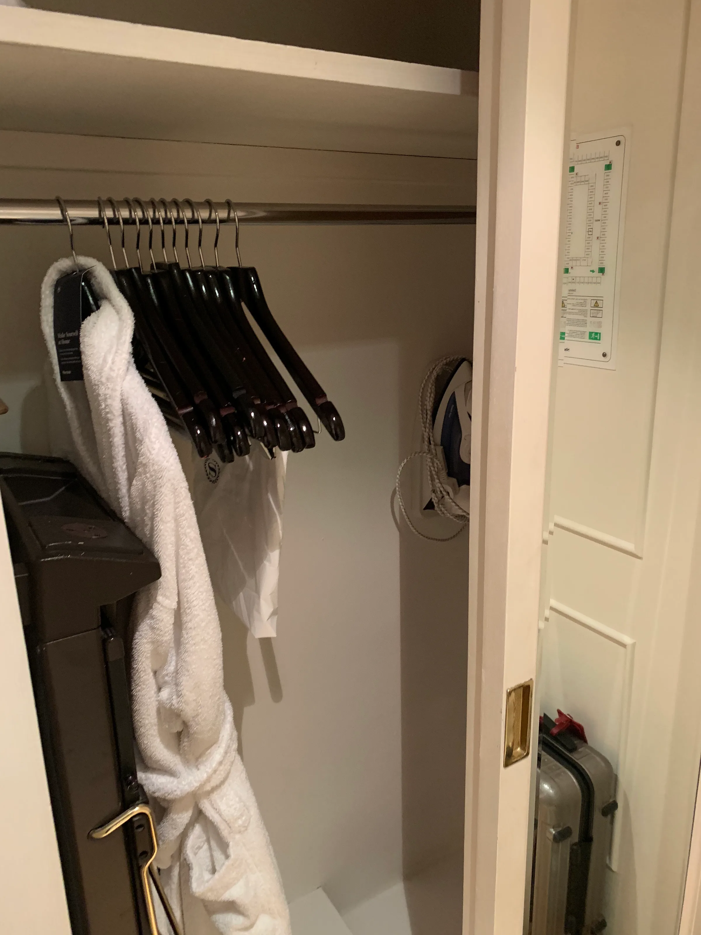 Schrank mit Kleiderbügeln und Handtuch im Hotelzimmer