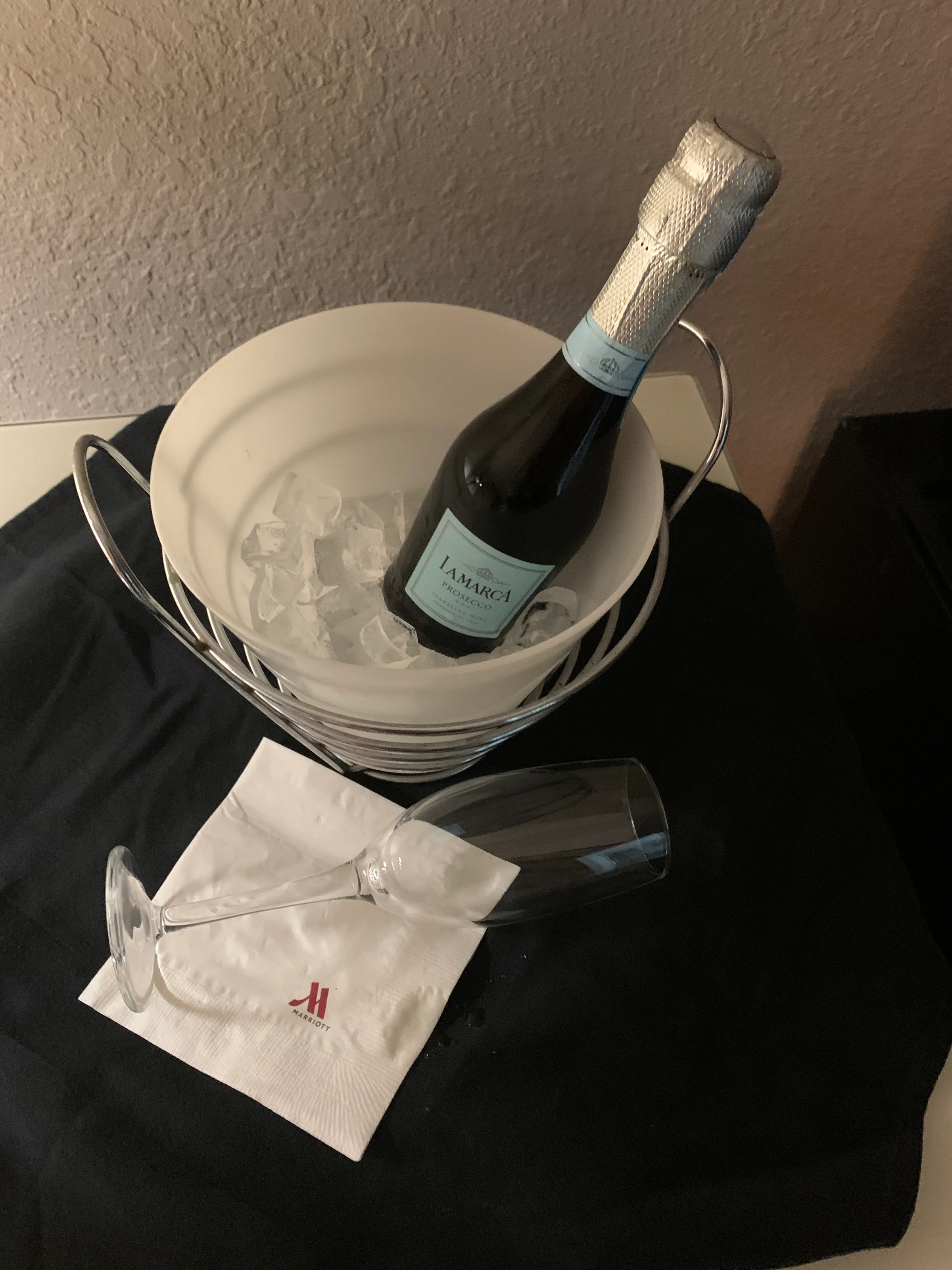 Eisgefüllter Champagnerkühler mit Flasche und Glas auf Serviette