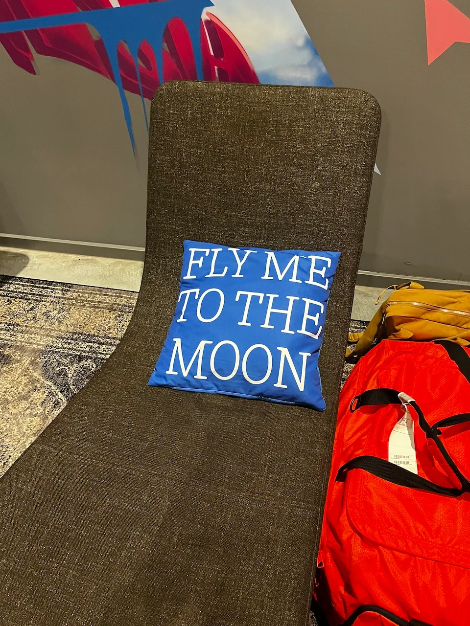 Sitzkissen mit Aufschrift 'FLY ME TO THE MOON' auf einem Stuhl