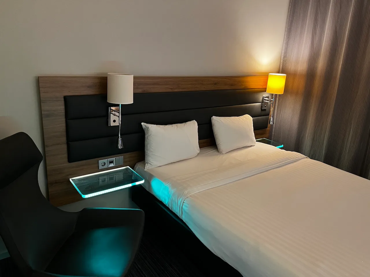 Hotelzimmer mit Doppelbett und Nachttisch mit beleuchteter Oberfläche